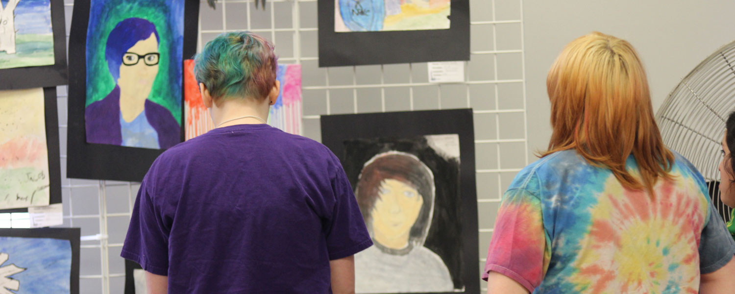 two students looking at student paintings 