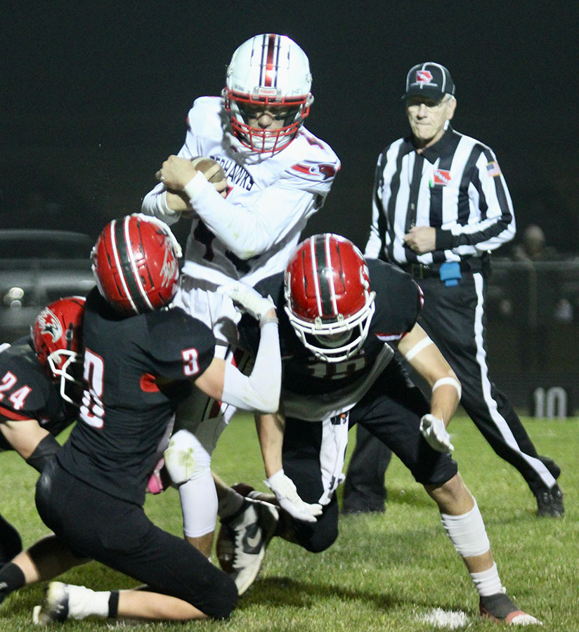 North Mahaska football player running with ball escaping the tackle of the opposing team.